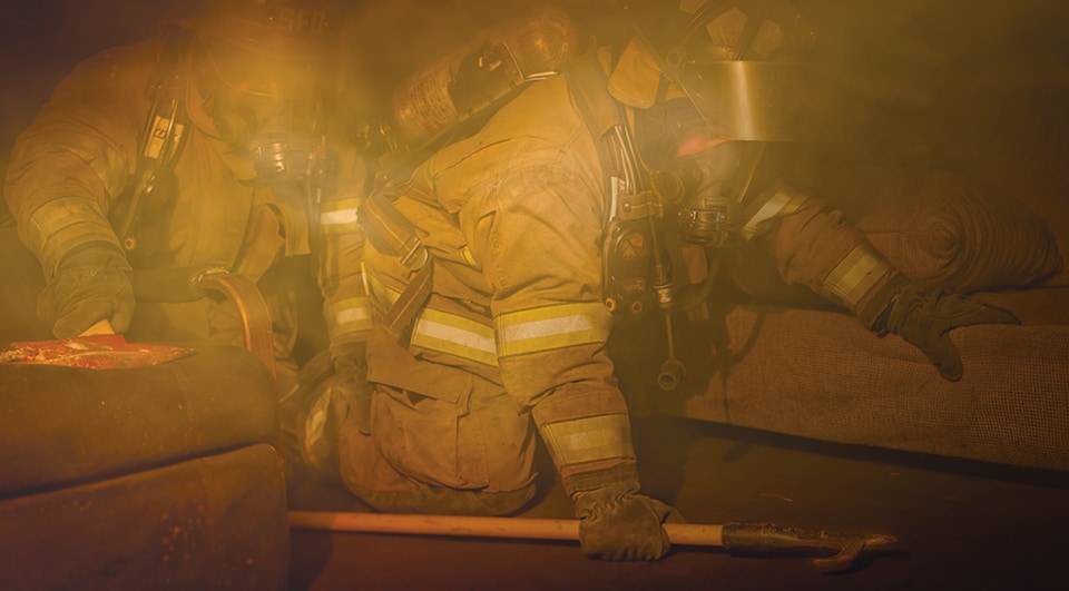Firefighters crawling through a smoke-filled building