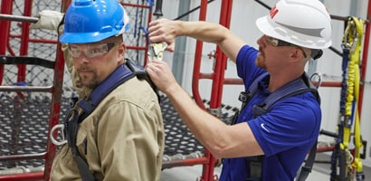 Instructor inspecting connection on workers harness
