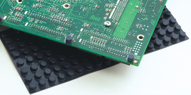 Close-up de una placa de circuito colocado sobre una lámina de bumpons.
