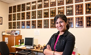 3M Corporate scientist, Jayshree Seth standing before plaques awarded to her for each of her patents.