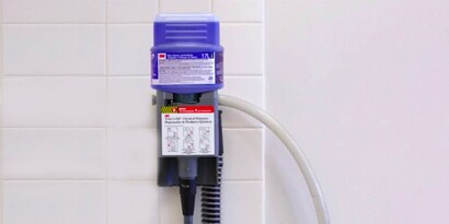 3M™ Twist ’n Fill™ Cleaning Chemical Management System with chemicals, mounted on a wall.
