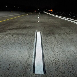 Roadway at night with white reflective centerline markings.