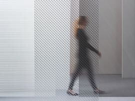 3M™ Glass Finishes blur the view of a woman walking past a window while shades of light still show.