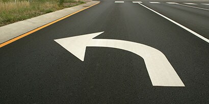 Large left-turn arrow on pavement in road’s turn lane.
