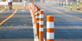 Line of orange bollards with white reflective tape to distinguish protected lane on road.
