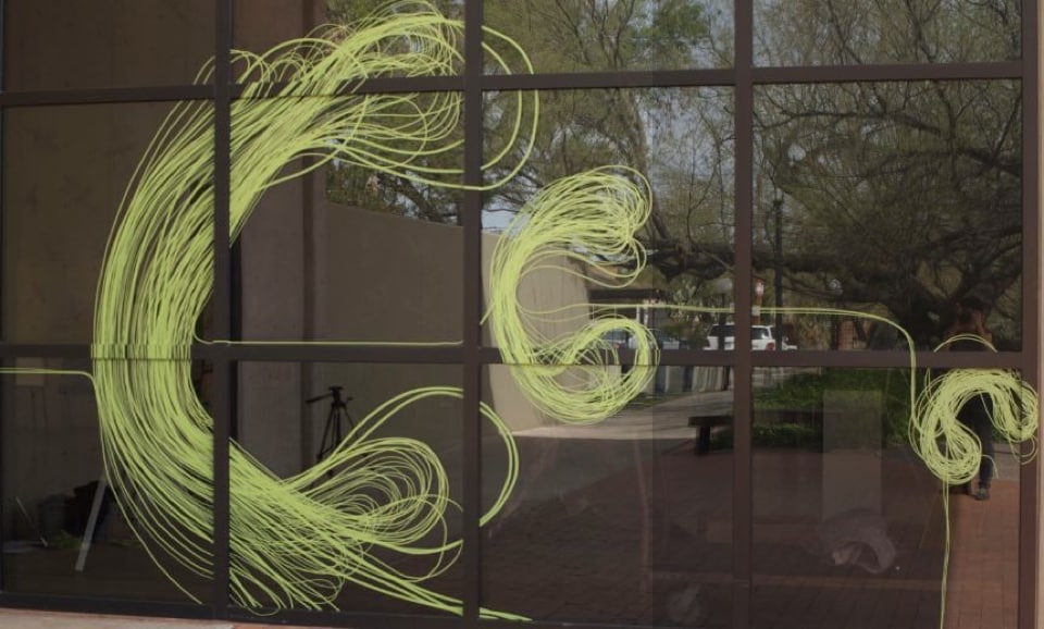 Karine Fellini&rsquo;s artwork made from Scotch Performance Masking Tape. Green lines of tape create colorful artwork on a window.