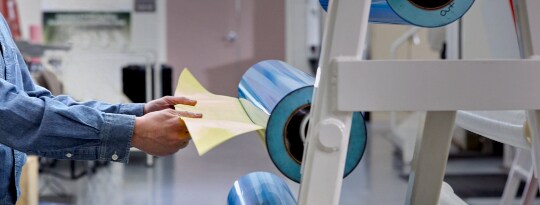 Image of a worker removing flexo tape from a cylinder

